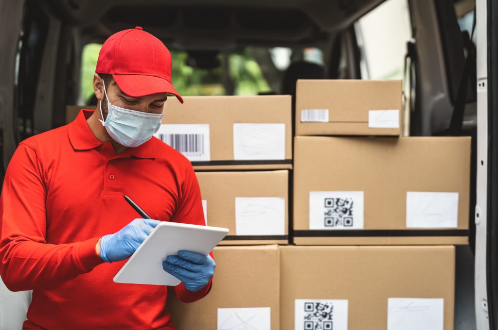Delivery man wearing face protective mask to avoid corona virus spread - Young express courier working during coronavirus outbreak - Deliver and online buying concept