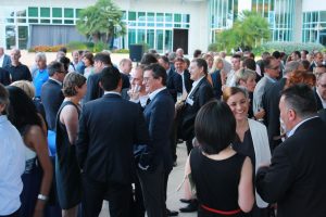Les invités sont rassemblés sur une terrasse au bord de la piscine de l'hôtel. Ils discutent.
